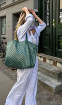 Woman carrying green patterned Élodie tote bag with detachable pouch on city street