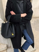Black Piana bucket bag in premium vegan leather with golden lock detail worn with black coat and jeans