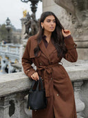 Stylish black Piana bucket bag in premium vegan leather with gold hardware, held by woman in brown coat outdoors