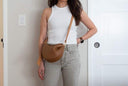 Woman wearing Toscana brown leather cross body bag with adjustable strap and curved design