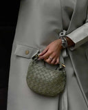 Orla woven handbag with leather design and gold-tone hardware held by woman in gray coat