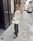 Woman carrying Loriana Crossbody Handbag in white vegan leather with silver logo on city street