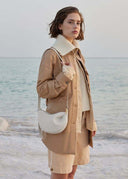 Toscana cross body bag with curved shape and smooth texture worn by woman by the beach