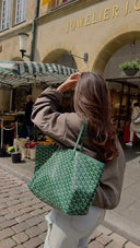 Woman carrying a green patterned Élodie tote bag with matching detachable pouch on city street